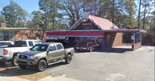 A restaurant named "Tony's" with a red and white roof, surrounded by parked trucks in a tree-lined area.