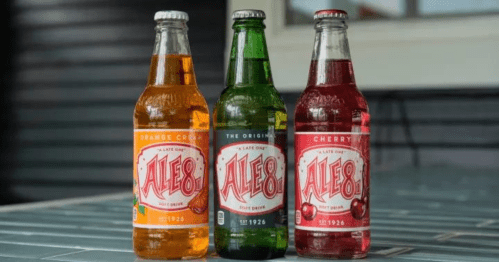 Three bottles of Ale-8 soft drinks: orange cream, original green, and cherry, displayed on a table.