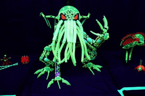 A glowing, intricate model of a creature with tentacles and claws, made from various colorful materials.