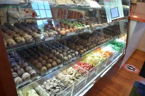 A display case filled with a variety of colorful chocolates and candies, neatly arranged in rows.