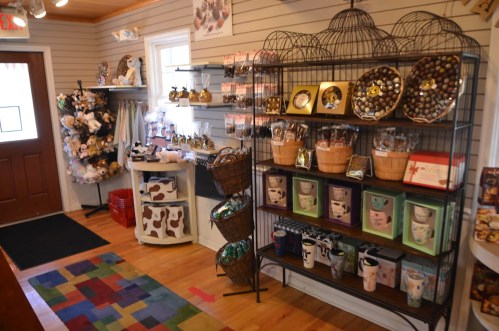 A cozy shop interior featuring shelves of gifts, baskets, and colorful rugs, creating a warm and inviting atmosphere.