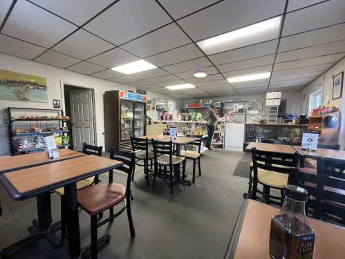 A cozy café interior with tables, a counter displaying snacks, and a person browsing the shelves.