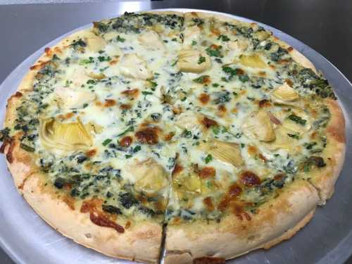 A freshly baked pizza topped with artichokes, cheese, and green herbs on a golden crust.