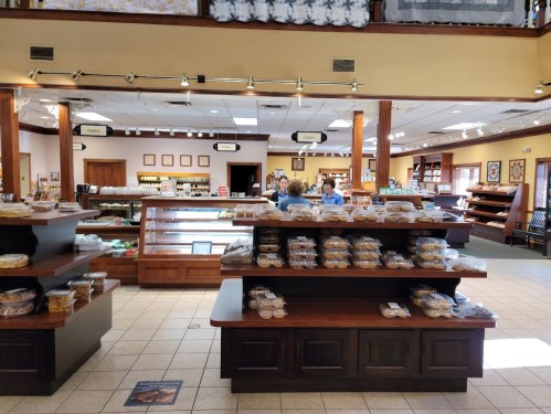 A bakery interior with display cases filled with baked goods and customers browsing in a bright, inviting space.