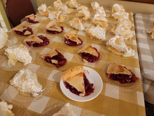 A table covered with slices of cherry pie and meringue pie on paper plates.
