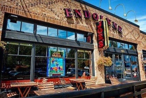 Exterior of Endolyne Joe's restaurant with large windows, outdoor seating, and a colorful poster in the window.