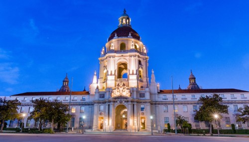 Historic building illuminated at dusk, featuring ornate architecture and a prominent dome against a blue sky.