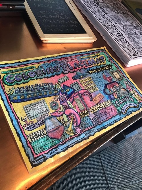 A colorful, illustrated placemat for coloring, featuring various whimsical designs and text about a prize contest.