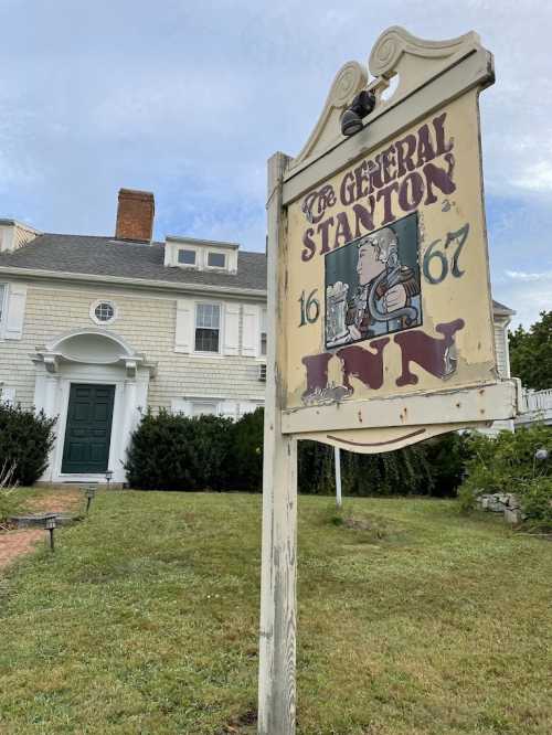 Sign for The General Stanton, established in 1667, in front of a historic building with a green door and manicured lawn.