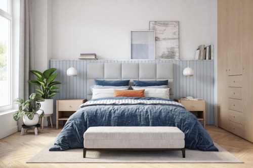 Modern bedroom with a gray upholstered bed, blue bedding, wooden furniture, and a potted plant by the window.