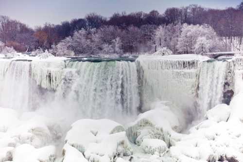 A snowy landscape featuring a frozen waterfall surrounded by trees, creating a serene winter scene.