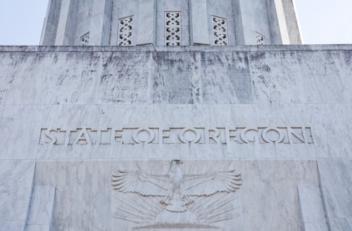 Close-up of the Oregon State Capitol building's marble facade, featuring the inscription "STATE OF OREGON" and an eagle emblem.
