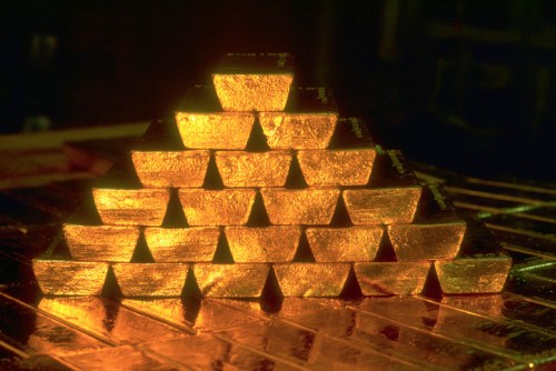 A pyramid of gleaming gold bars stacked neatly, reflecting warm light.