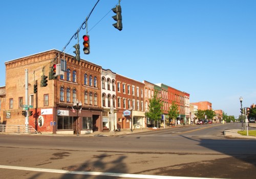 A quiet street scene featuring historic brick buildings and traffic lights under a clear blue sky.