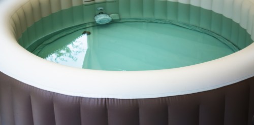 An inflatable hot tub filled with clear water, featuring a smooth, cushioned exterior.