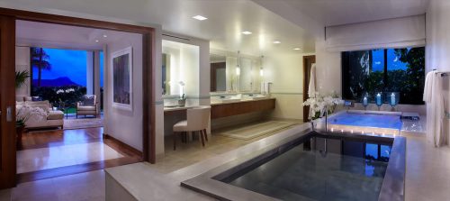 Luxurious bathroom with a soaking tub, modern fixtures, and a view of a living area and outdoor scenery.