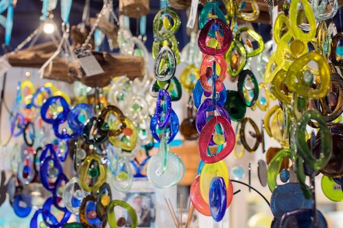 Colorful glass ornaments in various shapes and sizes hang from strings, creating a vibrant display.