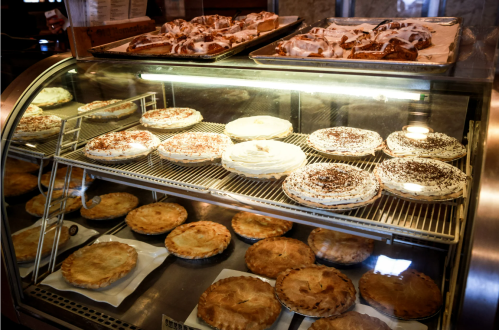 A display case filled with various pies and pastries, including cream pies and fruit-filled pies.