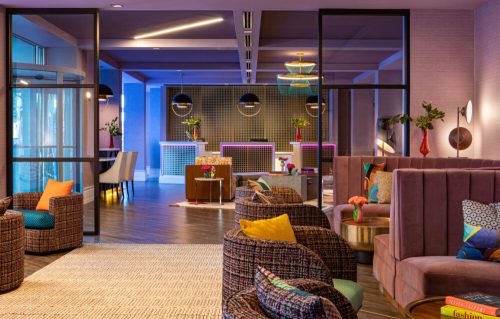 Modern hotel lobby featuring colorful seating, stylish decor, and a vibrant reception area with ambient lighting.