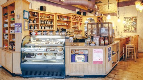 Cozy café interior featuring a display case of pastries, wooden shelves, and a warm, inviting atmosphere.