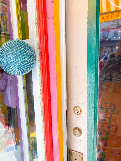 Colorful doorframe with vibrant stripes and a blue decorative ball hanging nearby.