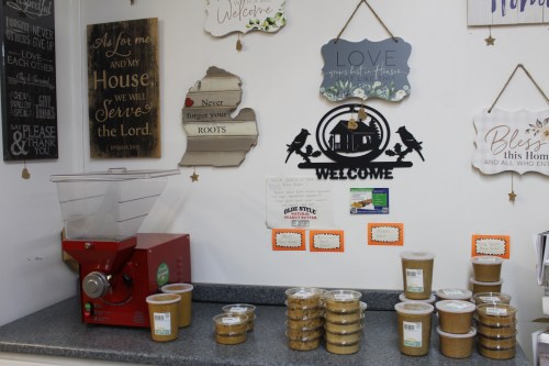 A cozy display with jars of goods, a red grinder, and various decorative signs on a wall.