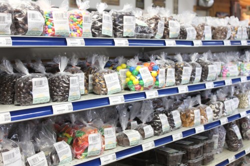 A colorful display of various candies in clear bags on shelves, showcasing a variety of sweets and treats.