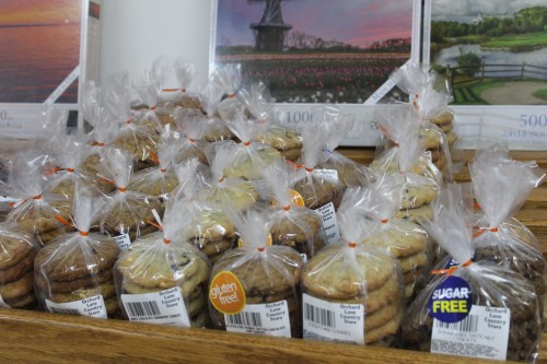 A display of packaged cookies, labeled gluten-free and sugar-free, arranged on a wooden table.