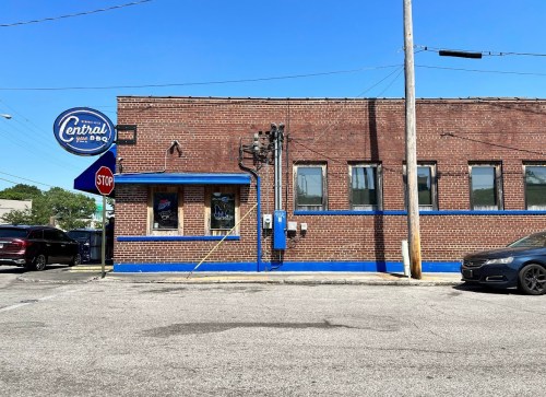 A brick building with blue accents and a sign reading "Central" on a sunny day, viewed from the street.