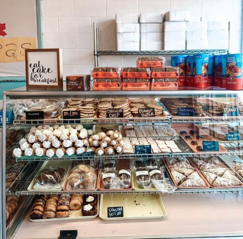 A display case filled with various baked goods, including cookies, bars, and pastries, with labels for each type.