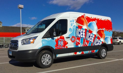 A colorful ice cream truck featuring large graphics of icee drinks parked in a lot.