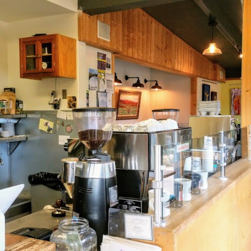 A cozy café interior featuring a coffee grinder, espresso machine, and wooden accents.