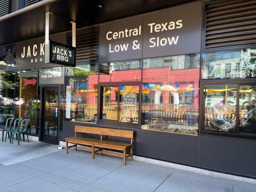 Exterior of Jack's BBQ featuring a wooden bench, large windows, and signage for "Central Texas Low & Slow."