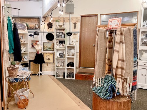 A cozy shop interior featuring vintage decor, scarves, and shelves with various collectibles and accessories.