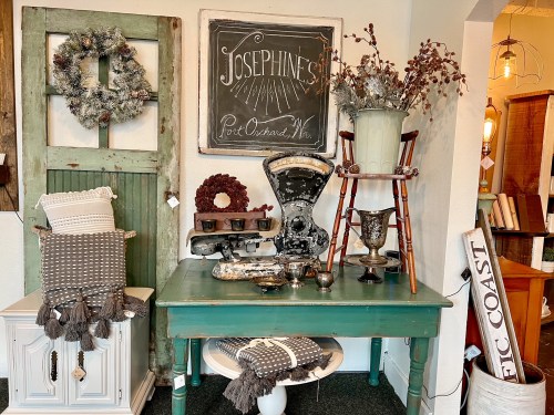 A cozy display featuring vintage decor, a green table, and various decorative items in a charming shop setting.