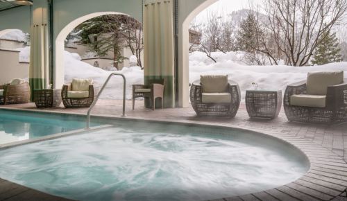 A serene indoor hot tub surrounded by cozy seating and snowy outdoor scenery.