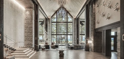 A spacious, modern lobby with stone walls, large windows, and elegant furnishings, overlooking a scenic outdoor view.