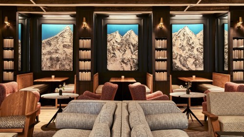 Cozy lounge with mountain artwork, wooden furniture, and soft seating, creating a warm and inviting atmosphere.