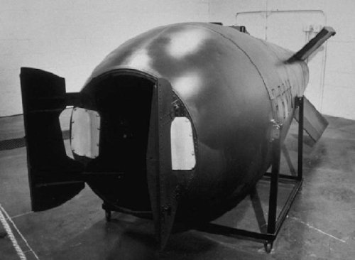A large, cylindrical black object resembling a submarine, displayed on a stand in a warehouse-like setting.