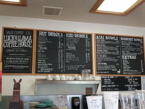 Menu board at Lucky Llama Coffee House featuring hot drinks, iced drinks, acai bowls, and breakfast options.