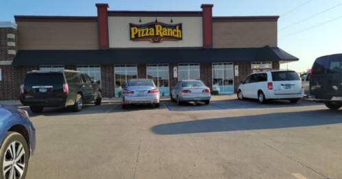 Exterior of Pizza Ranch restaurant with parked cars in front and clear blue sky above.