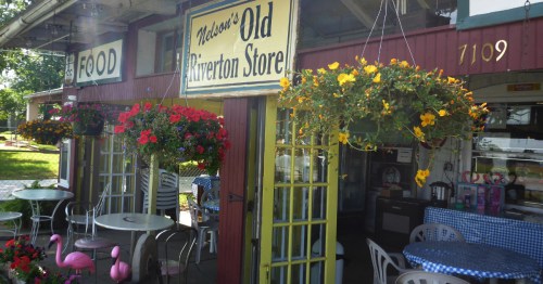 Outdoor seating area of Nelson's Old Riverton Store on Route 66 with hanging flowers and pink flamingos.
