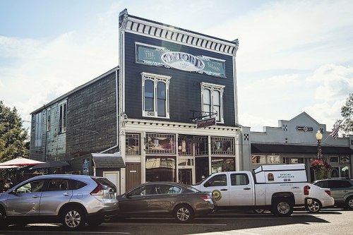 Historic building with a sign reading "The Oxford" and parked cars in front, set against a clear blue sky.