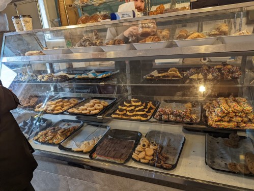 A display case filled with various baked goods, including cookies, pastries, and colorful treats.