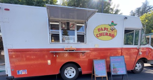 A red and white food truck named "Papi Churro" with a closed sign and chalkboard menus outside.