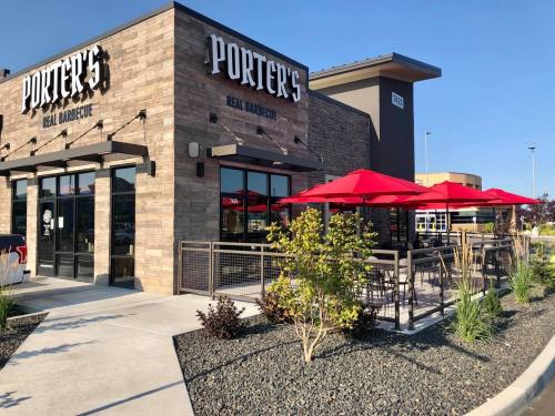 Exterior of Porter's Real Barbecue restaurant with red umbrellas and a landscaped patio on a sunny day.