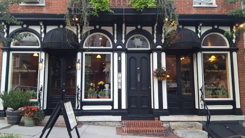 Exterior of a charming restaurant with black and white architecture, large windows, and flower arrangements.