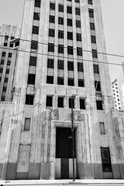 A tall, vintage building with a marble facade and decorative elements, captured in black and white.
