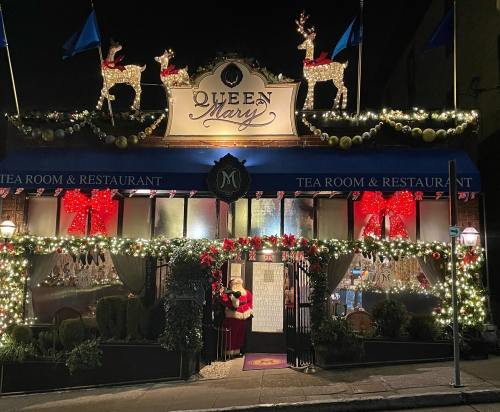 A festive restaurant entrance decorated with lights, wreaths, and reindeer, set against a night sky.