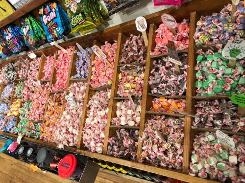 A colorful display of assorted candies in wooden bins, featuring various shapes and flavors.